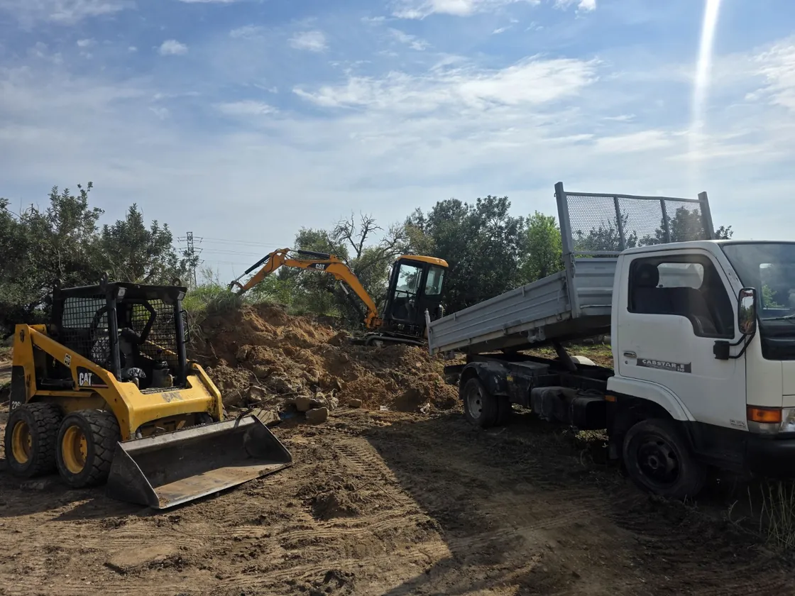 Minicargadora y camión trabajando en movimiento de tierras